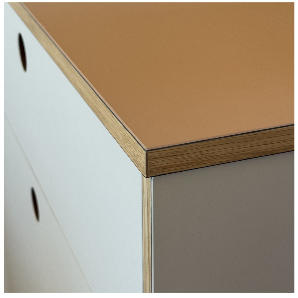 Arbeitsplatte Küche - Kantenausbildung Close-up of a modern cabinet corner showing a brown laminate top, white side panel with circular holes, and beige lower panel.